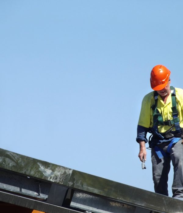Tradesman wearing a hard hat while working up on the roof